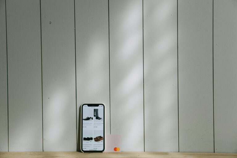 A smartphone and credit card sit on a wooden surface with soft lighting shadows.